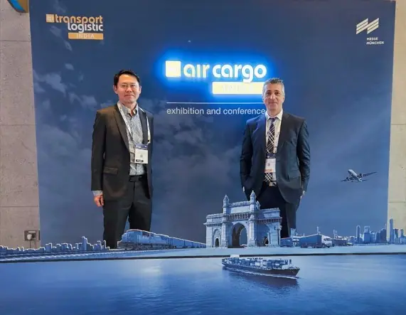 Two ALS managers at the Air Cargo India 2024 backdrop with Gateway of India artwork in Mumbai