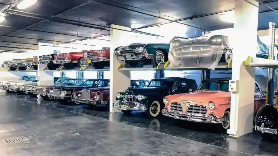 Vintage classic cars with chrome grilles stored on two-level car stacker lifts in a private garage at Al Manara, Dubai