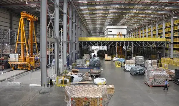Cargo hall at dnata Freight Gate 5, Dubai, with a yellow elevating transfer vehicle, ULD storage racks and netted pallets