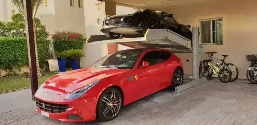 Sports car raised on a car stacker lift above a second parked car at a private villa in The Lakes, Dubai